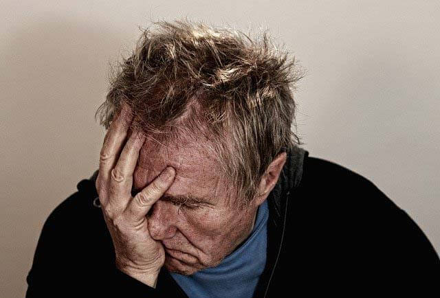 un homme en dépression qui se tient la tête