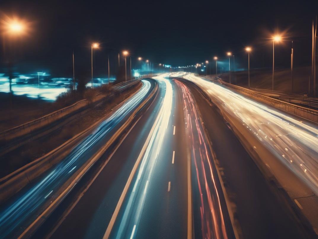 Exposition longue montrant les lumières floues des voitures passant sur une autoroute faiblement éclairée, symbolisant une vision floue causée par l'astigmatisme, dans des tons bleutés profonds et peu saturés.