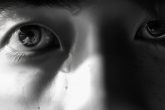 Gros plan sur un visage individuel, mettant en valeur le blanc au-dessus et au-dessous de ses yeux perçants, illuminé par des rayons de lumière douce, représentant l'essence des yeux Sanpaku, en style monochrome, regard intense, minimaliste, qualité 4K nette.