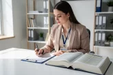 Un ergothérapeute examine une ordonnance près d’un ouvrage juridique ouvert dans un bureau lumineux.
