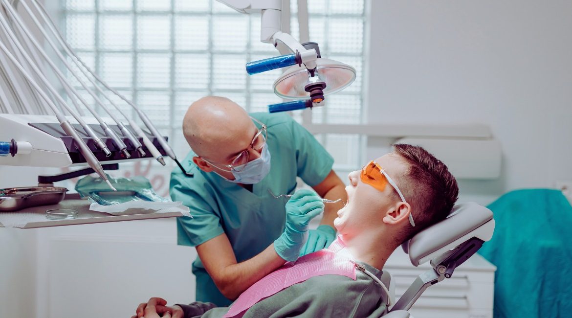 Dentiste examinant la bouche d'un patient installe au fauteuil dans un cabinet dentaire