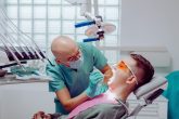 Dentiste examinant la bouche d'un patient installe au fauteuil dans un cabinet dentaire