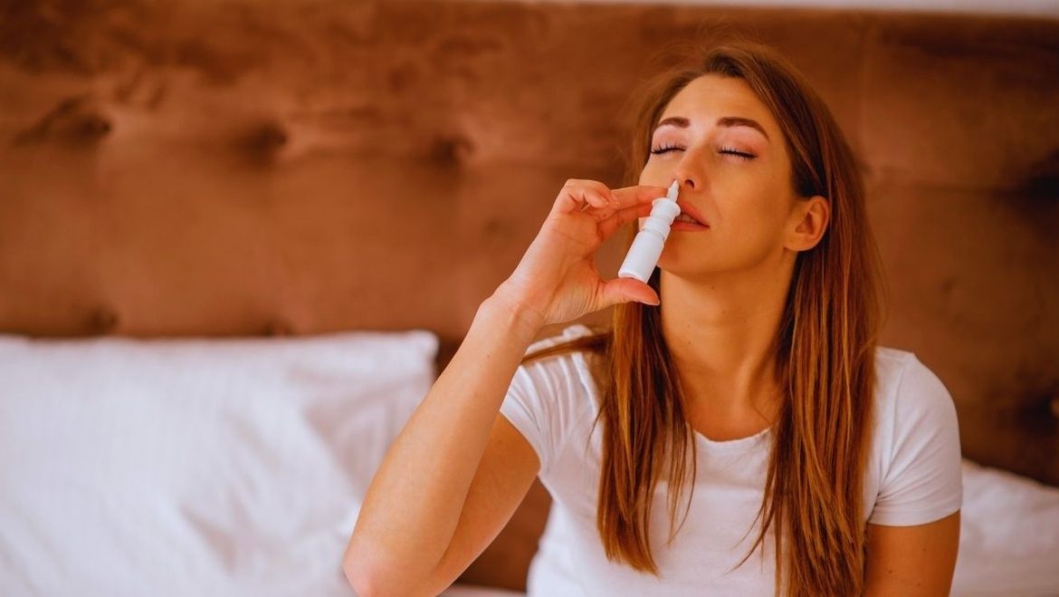 Femme adulte utilisant un spray nasal pour se laver le nez