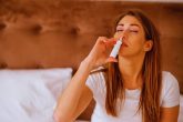 Femme adulte utilisant un spray nasal pour se laver le nez