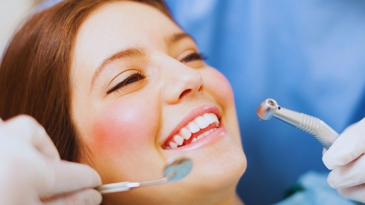 Patiente souriante sur le fauteuil pendant un détartrage chez le dentiste
