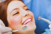 Patiente souriante sur le fauteuil pendant un détartrage chez le dentiste